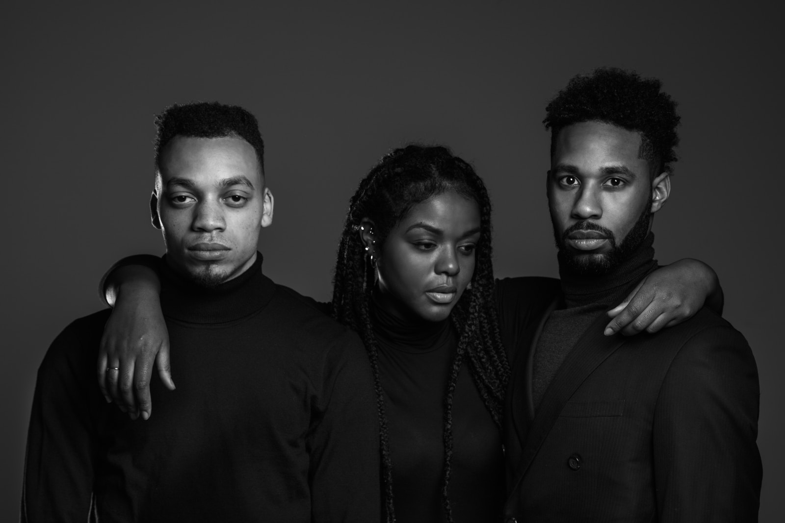 Photo by Jessica Felicio grayscale photo of woman standing between two men